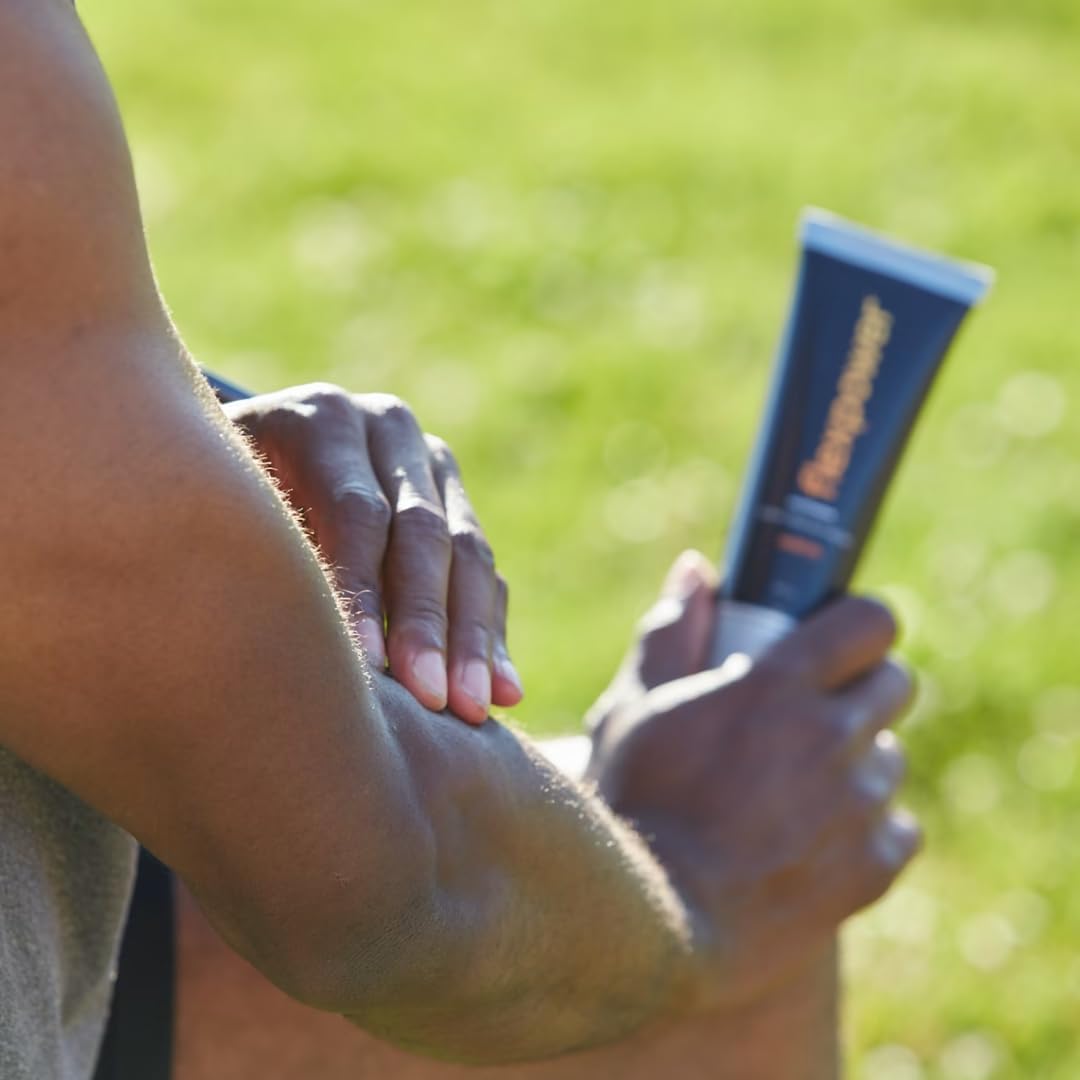 A person massages Flexpower Warm lotion into their elbow while holding the tube